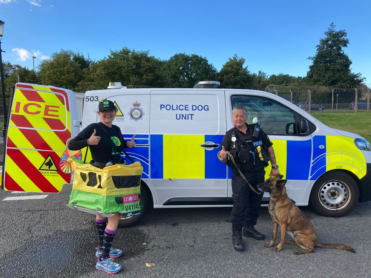 A runner standing in front of the Police Dog Unit van with a police officer and police dog