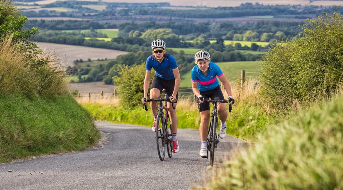 Two people cycling up a hill during a cycling event.