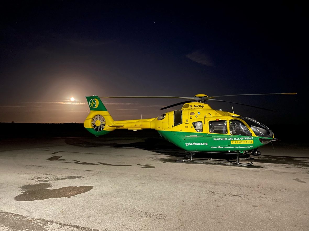 A grounded helicopter at night with a full moon in the background