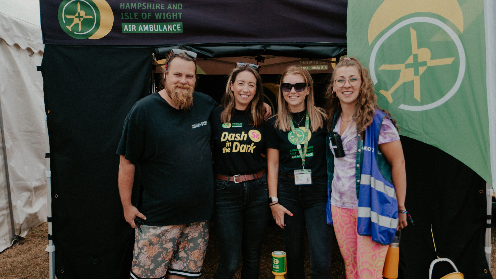 Four people stood in front of a HIOWAA gazebo in a field.