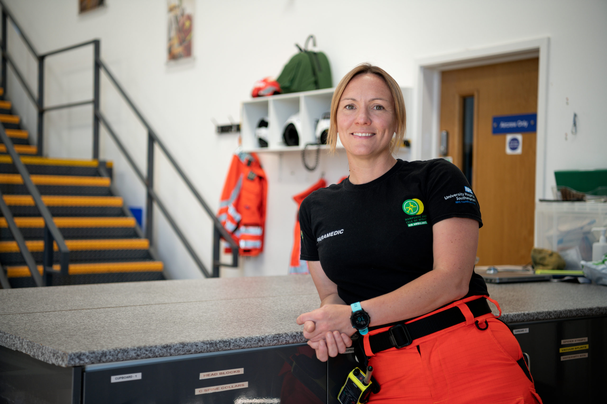 Specialist Paramedic Clare Fitchett leaning against a worktop in an air ambulance hangar.