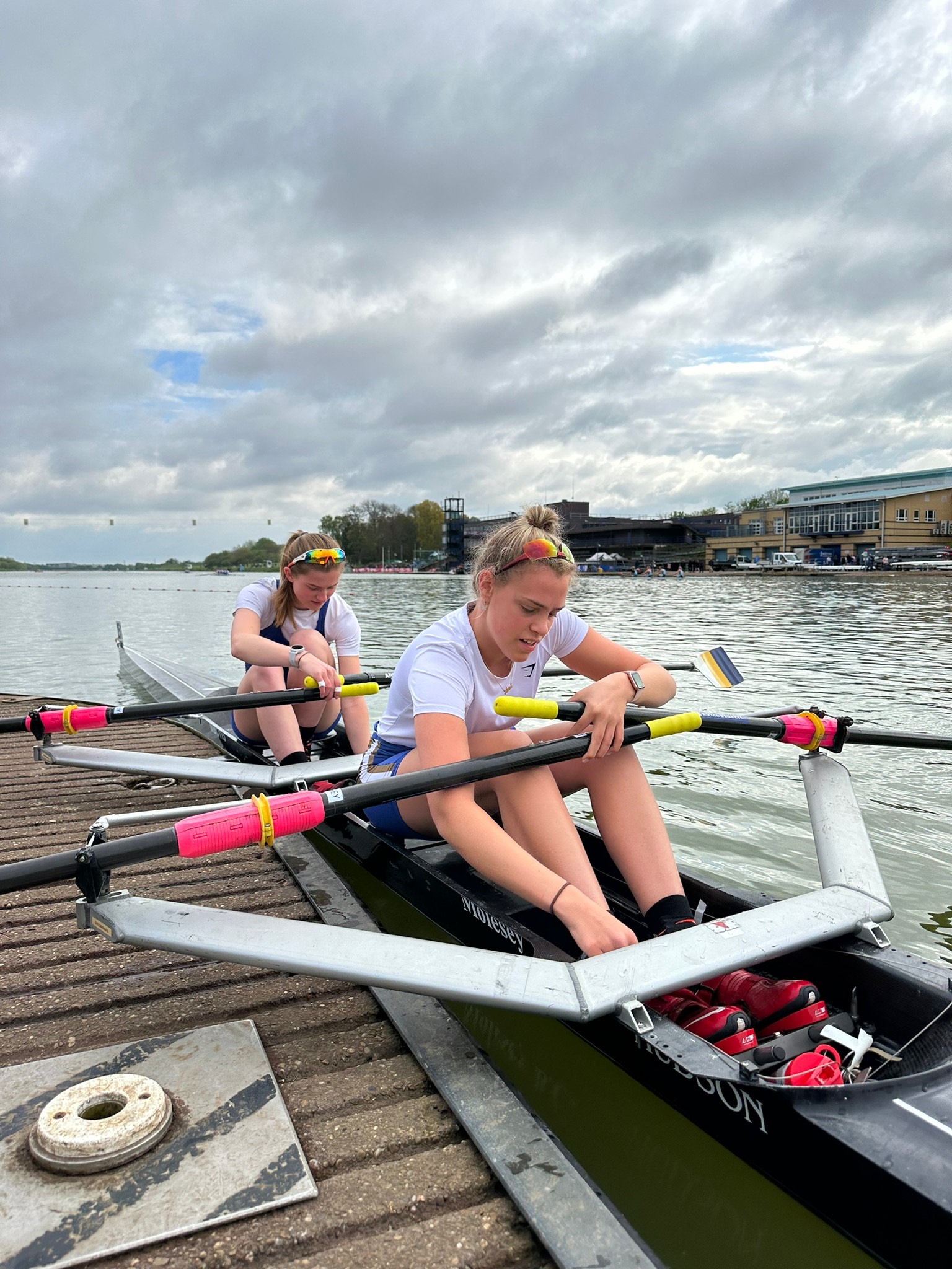 Two people sat in a docked rowing boat.