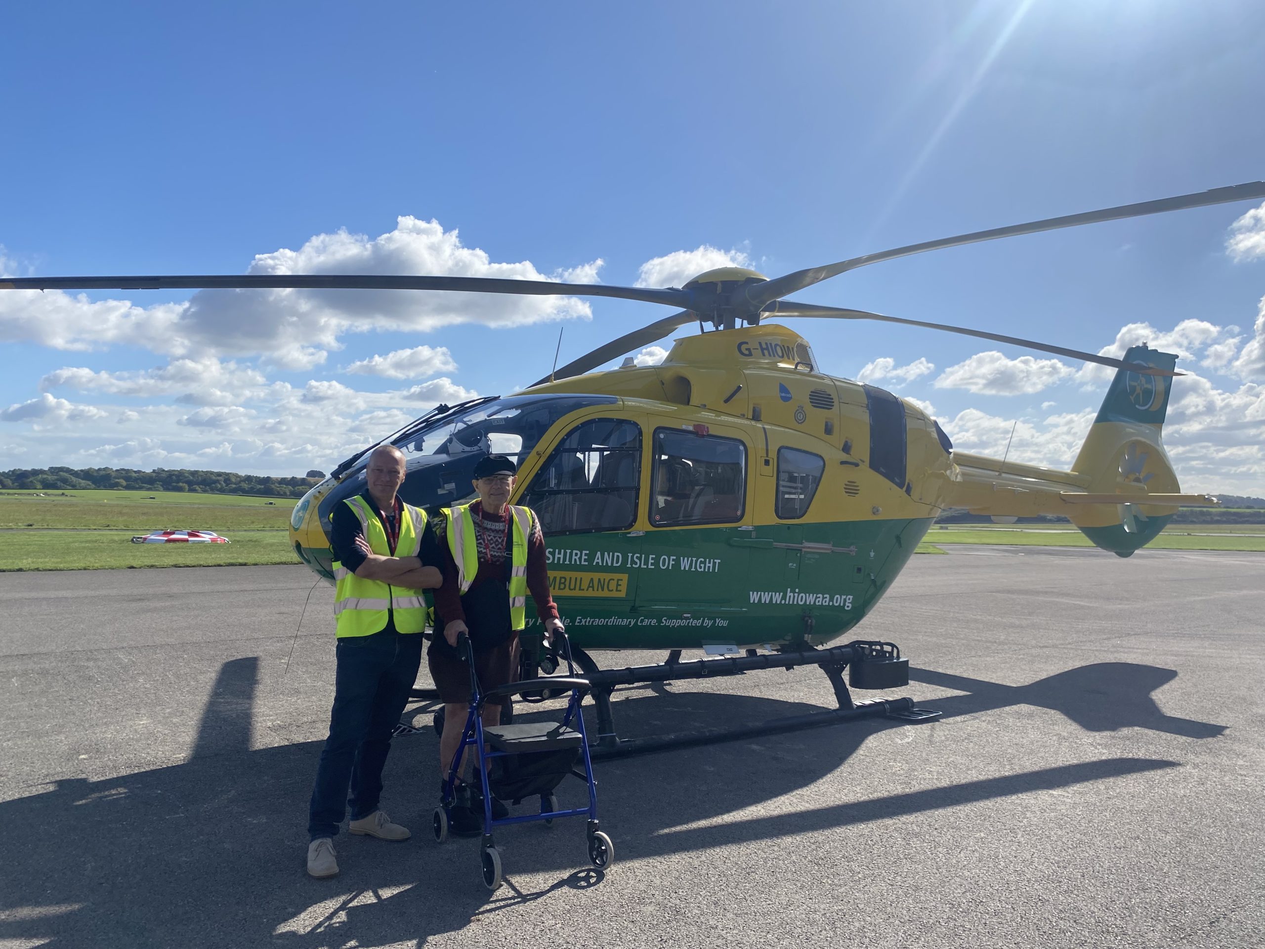 Two people stood in front of a helicopter.