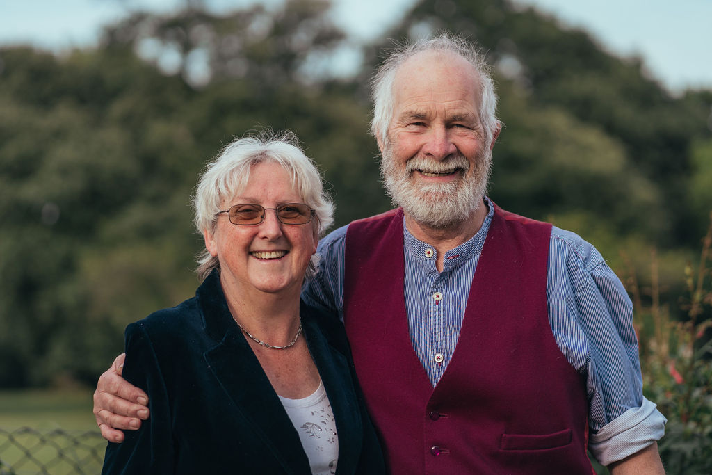 A man and a woman stood side by side smiling at the camera.