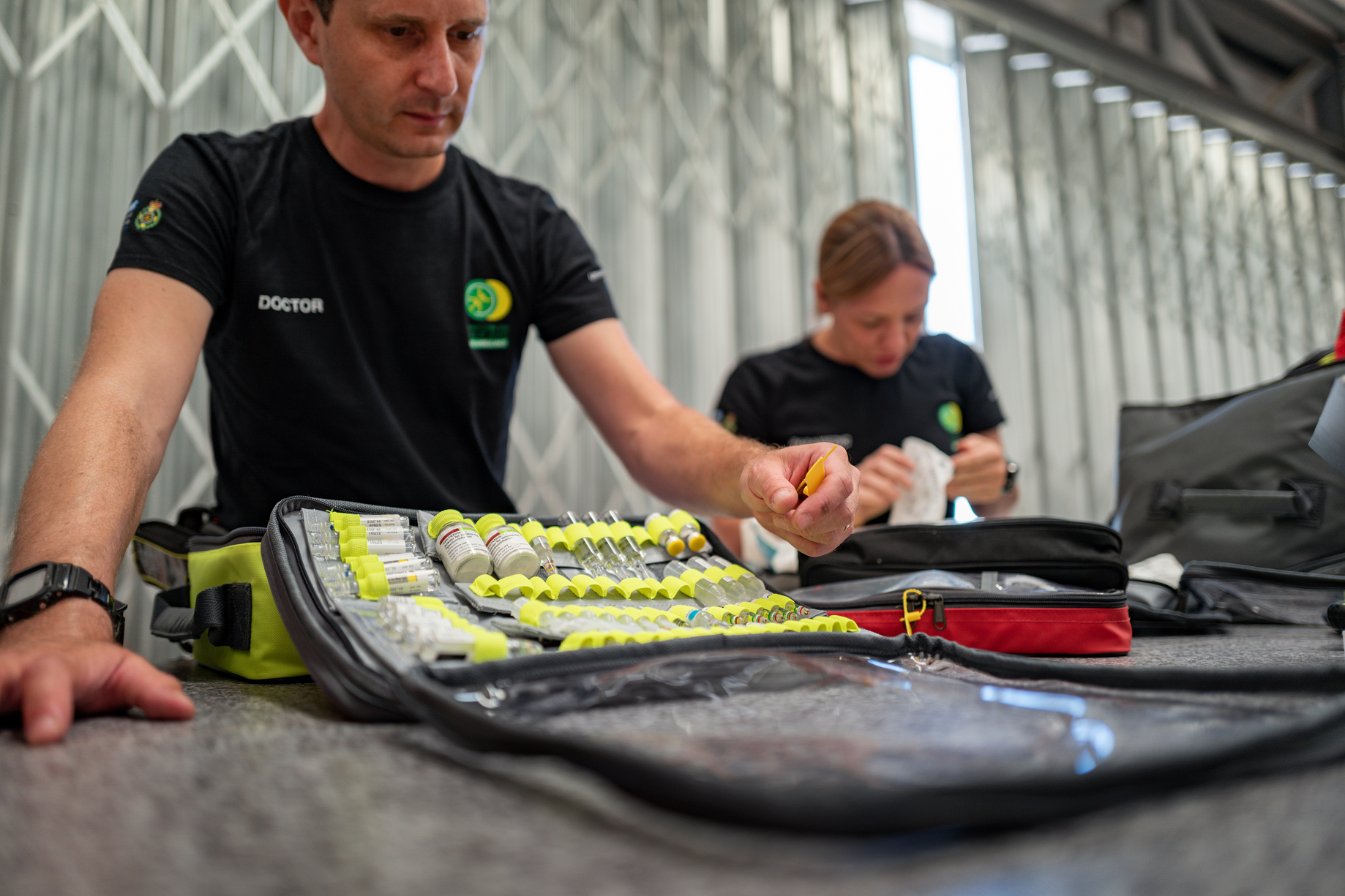 Air ambulance crew members in a hangar inspecting bags of kits and medications.