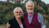 A man and a woman stood side by side smiling at the camera.