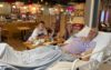 A family in a hospital coffee shop. The husband and father is lying in a hospital bed next to the table.